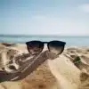 Black sunglasses sitting on a pile of sand at the beach