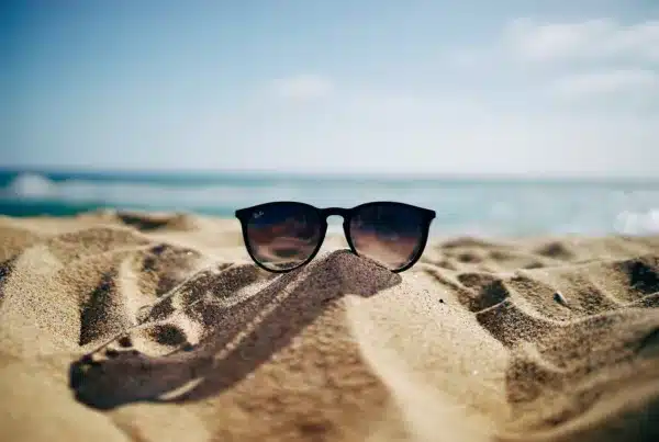 Black sunglasses sitting on a pile of sand at the beach