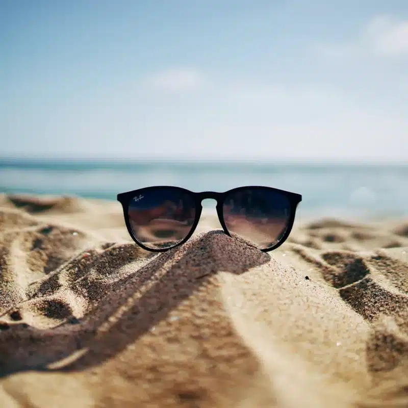 Black sunglasses sitting on a pile of sand at the beach