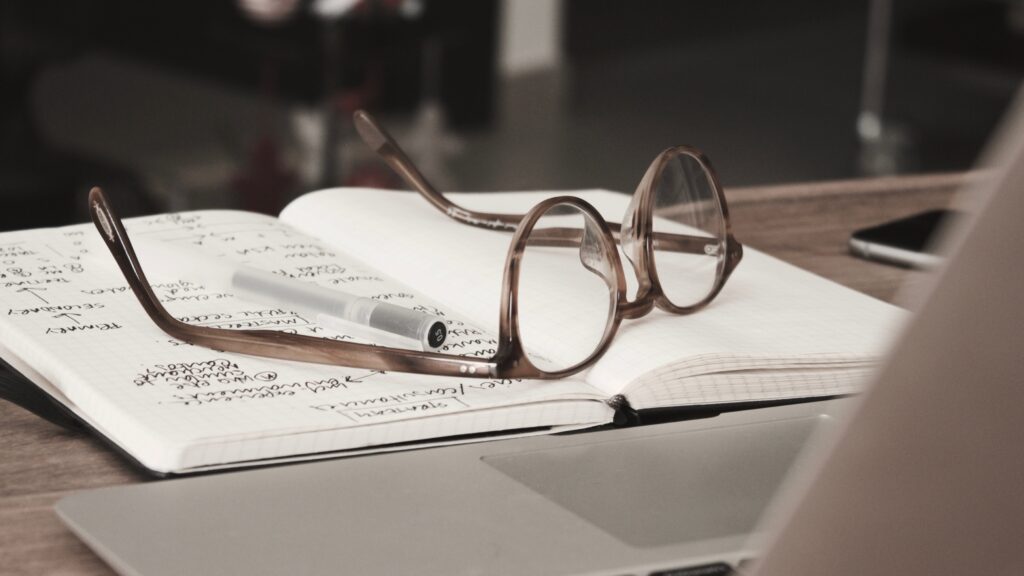Stylish Gray-Framed Eyeglasses Resting atop a Notebook: A Perfect Blend of Fashion and Function