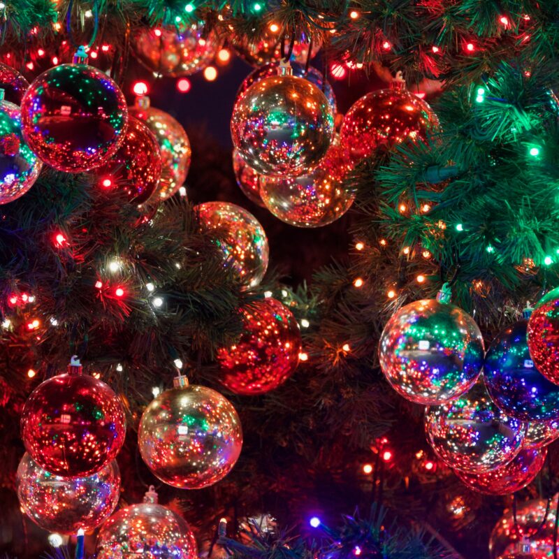 Red and Green Baubles on Christmas Tree With Lights Lit Up